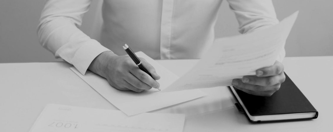 young-businessman-sitting-at-table-and-working-with-papers-darken