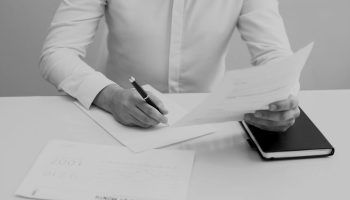 young-businessman-sitting-at-table-and-working-with-papers-darken